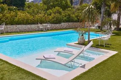 a pool with two lounge chairs and a palm tree at Villa laura in Palermo