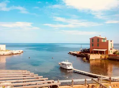 a boat is docked at a dock next to a building at Relaxing seahouse in Santa Flavia