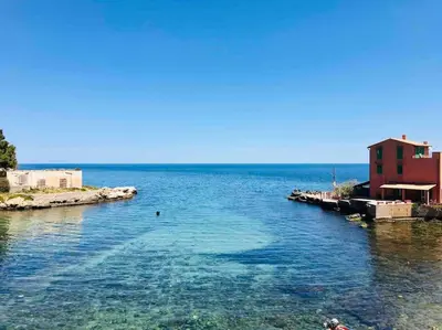 a view of a large body of water with a red building at Relaxing seahouse in Santa Flavia