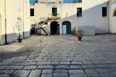 a stone courtyard with a building and a staircase at Loft Palermo Centro con terrazzo. Free parking in Palermo