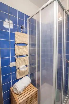 a blue tiled bathroom with a shower and towels at Appartamento del centro CIR 19081005C217988 in Castellammare del Golfo
