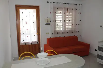 a living room with a table and a red couch at Turisti a Casa in San Vito lo Capo