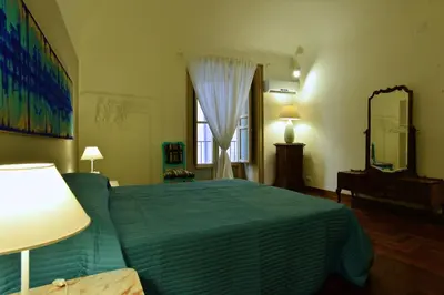 a bedroom with a green bed and a mirror at La Locanda dei Corrieri in Palermo