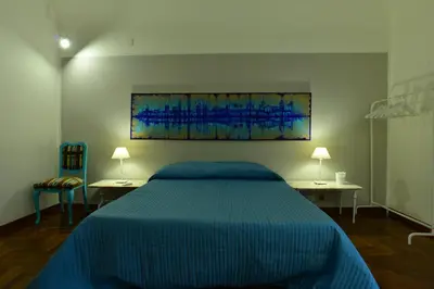 a bedroom with a blue bed with two tables and a painting at La Locanda dei Corrieri in Palermo