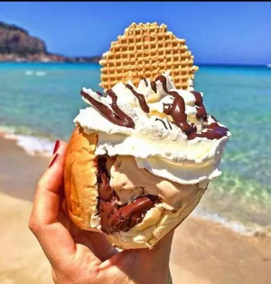 a person holding a waffle ice cream sandwich on the beach at casa giorgia mondello in Palermo