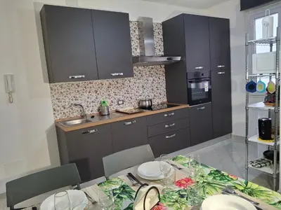a kitchen with a dining table and a kitchen with black cabinets at Casa Maria Rosa Deliziosa in Palermo