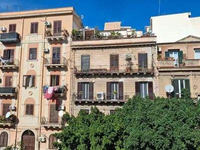an old building with balconies and trees in front of it at Casa Maria Rosa Deliziosa in Palermo