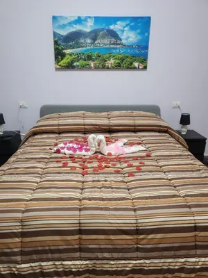 a bed with a striped bedspread with a picture on the wall at Sole nascente in Terrasini