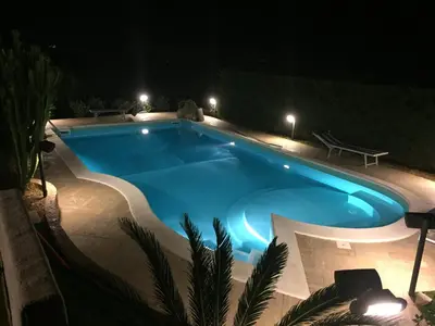 a swimming pool at night with a bench around it at Doppia villa indipendente/clara in Mandra Capreria