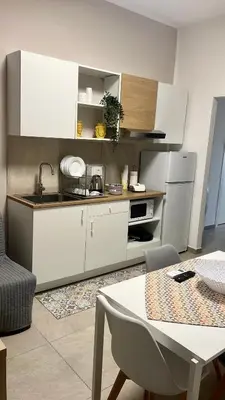 a kitchen with white cabinets and a table in a room at La Casa di Elisa Mini Apartment - Palermo in Palermo