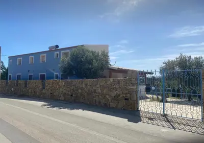 a fence next to a stone wall with a building at B&B Pelagos in Castellammare del Golfo