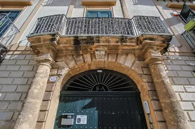 a building with a black door with a balcony above it at Casa Querencia rooms in Palermo