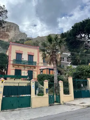 a house with a fence and a palm tree at FINESTRA SUL MARE in Palermo