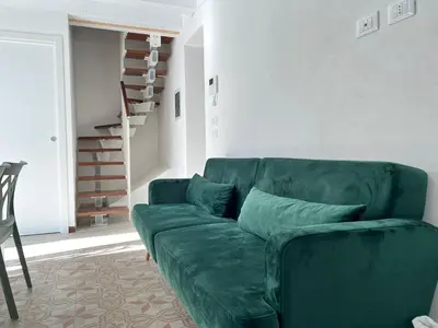 a green couch in a living room with a staircase at M'AMA apartment in Ficarazzi