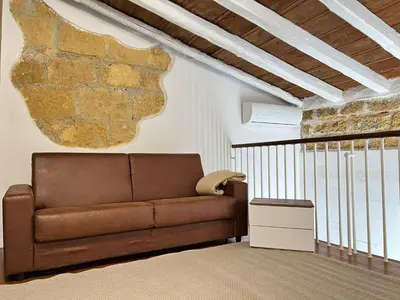 a brown couch in a living room with a stone wall at M'AMA apartment in Ficarazzi