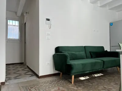 a green couch in a white room with a window at M'AMA apartment in Ficarazzi
