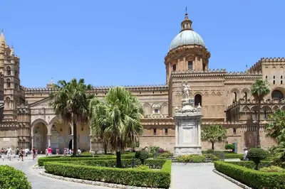 a building with a statue and palm trees in front of it at Wood House - Palermo in Palermo