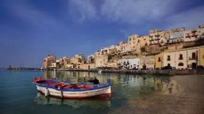 a boat sitting in the water next to a city at Ancilinas House in Castellammare del Golfo