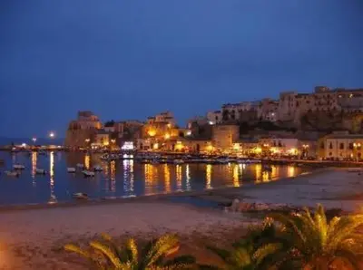 a city at night with boats in the water at Ancilinas House in Castellammare del Golfo