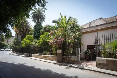 a street with a fence and trees and a building at Bibi house a San Giovanni degli Eremiti in Palermo
