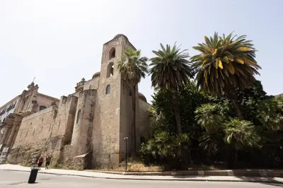 an old building with palm trees in front of it at Bibi house a San Giovanni degli Eremiti in Palermo