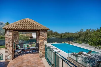 a stone gazebo next to a swimming pool at Villa Miceli in Scopello
