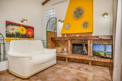 a living room with a fireplace and a white chair at Villa Miceli in Scopello