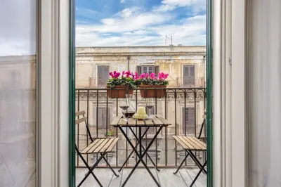 a balcony with a table with chairs and flowers on it at 70 Lab Apartment in Palermo