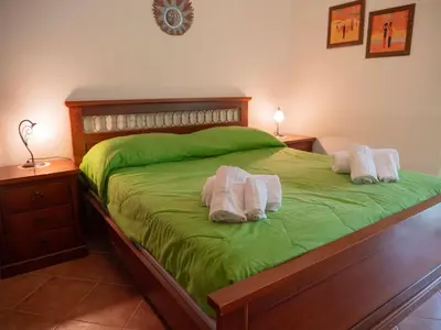 a bedroom with a green bed with two towels on it at VILLA ANGELA TRABIA in Trabia