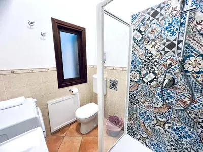a bathroom with a toilet and a mosaic wall at Casa Carlotta Apartments in Terrasini