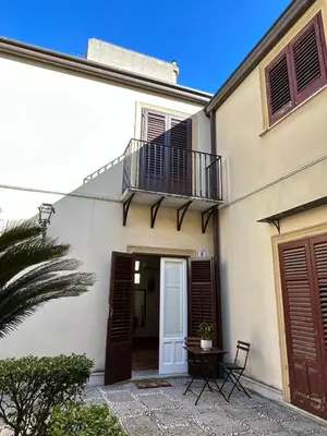 a white house with a balcony and a door at Corte dei Re di Palermo Apartment in Palermo