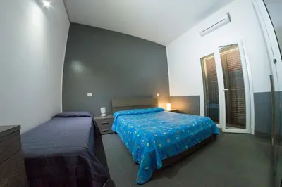 a bedroom with two beds with blue sheets and a window at Villa Giambona in Isola delle Femmine