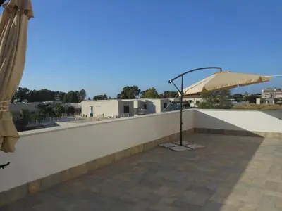 a patio with an umbrella on the roof at Villa Giambona in Isola delle Femmine