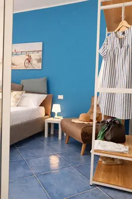 a bedroom with blue walls and a bed and a couch at Oikos Design Sicily in Castellammare del Golfo