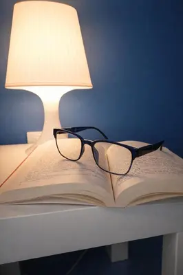 a book with glasses sitting on a table next to a lamp at Oikos Design Sicily in Castellammare del Golfo