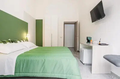 a green and white bedroom with a bed and a television at Case Billeci Casa Verde in Palermo
