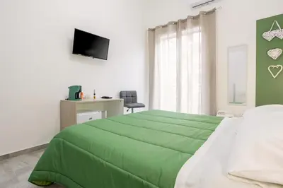 a green bed in a white room with a television at Case Billeci Casa Verde in Palermo