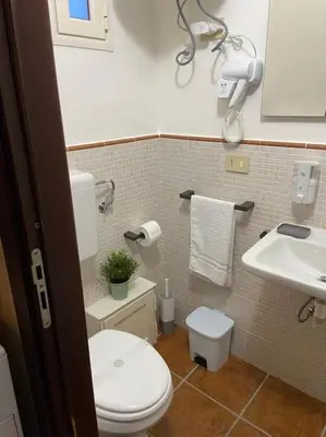 a bathroom with a white toilet and a sink at Petit Maison in Palermo