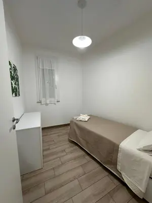 a bedroom with a bed and a table and a window at Casa Andrew in Terrasini