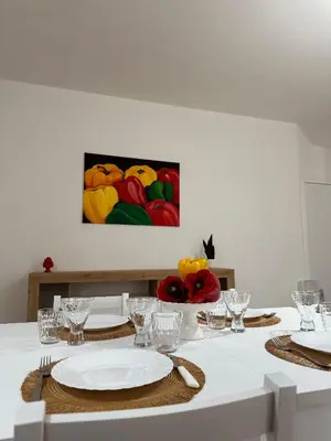 a table with plates and glasses and a painting on the wall at Casa Andrew in Terrasini