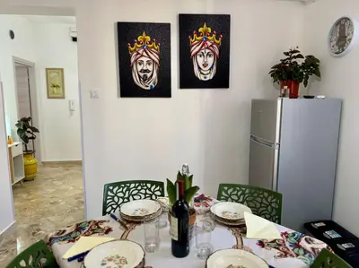 a dining room table with plates and a refrigerator at La Dimora di Anna e Ciccio in Casteldaccia