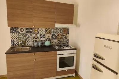 a small kitchen with a stove and a refrigerator at N'Amùri Casa Vacanze in pieno centro storico in Bagheria
