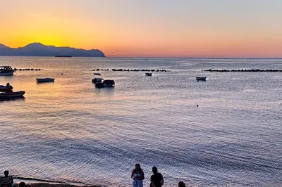 a group of people standing on the beach at sunset at N'Amùri Casa Vacanze in pieno centro storico in Bagheria