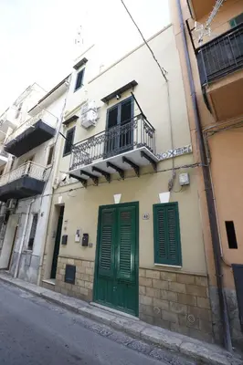 a building with green doors and a balcony at N'Amùri Casa Vacanze in pieno centro storico in Bagheria