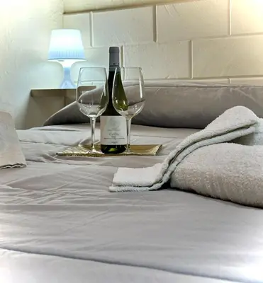 a bottle of wine and two glasses on a bed at Merlino Smarthouse alla Zisa in Palermo