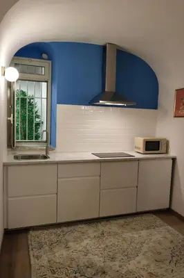 a kitchen with white cabinets and a blue wall at Due Sicilie Ballarò in Palermo