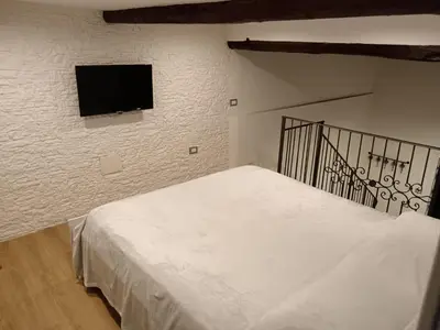 a bedroom with a bed with a tv on the wall at IGIEA APARTMENT in Palermo