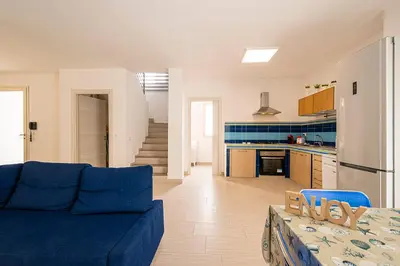 a living room with a blue couch and a kitchen at Borgo Aranci - Villa Unifamiliare Ibiscus 08 in Castellammare del Golfo