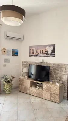 a living room with a flat screen tv on a brick wall at Mona House accogliente casa vacanza in Palermo