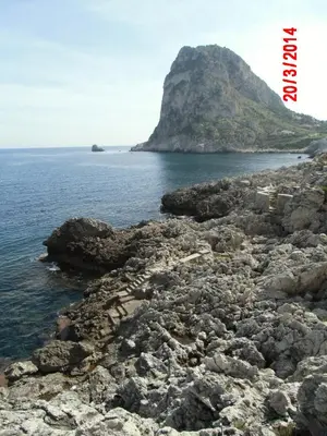 a rocky shore with a mountain in the background at Holiday home Santa Flavia in Santa Flavia